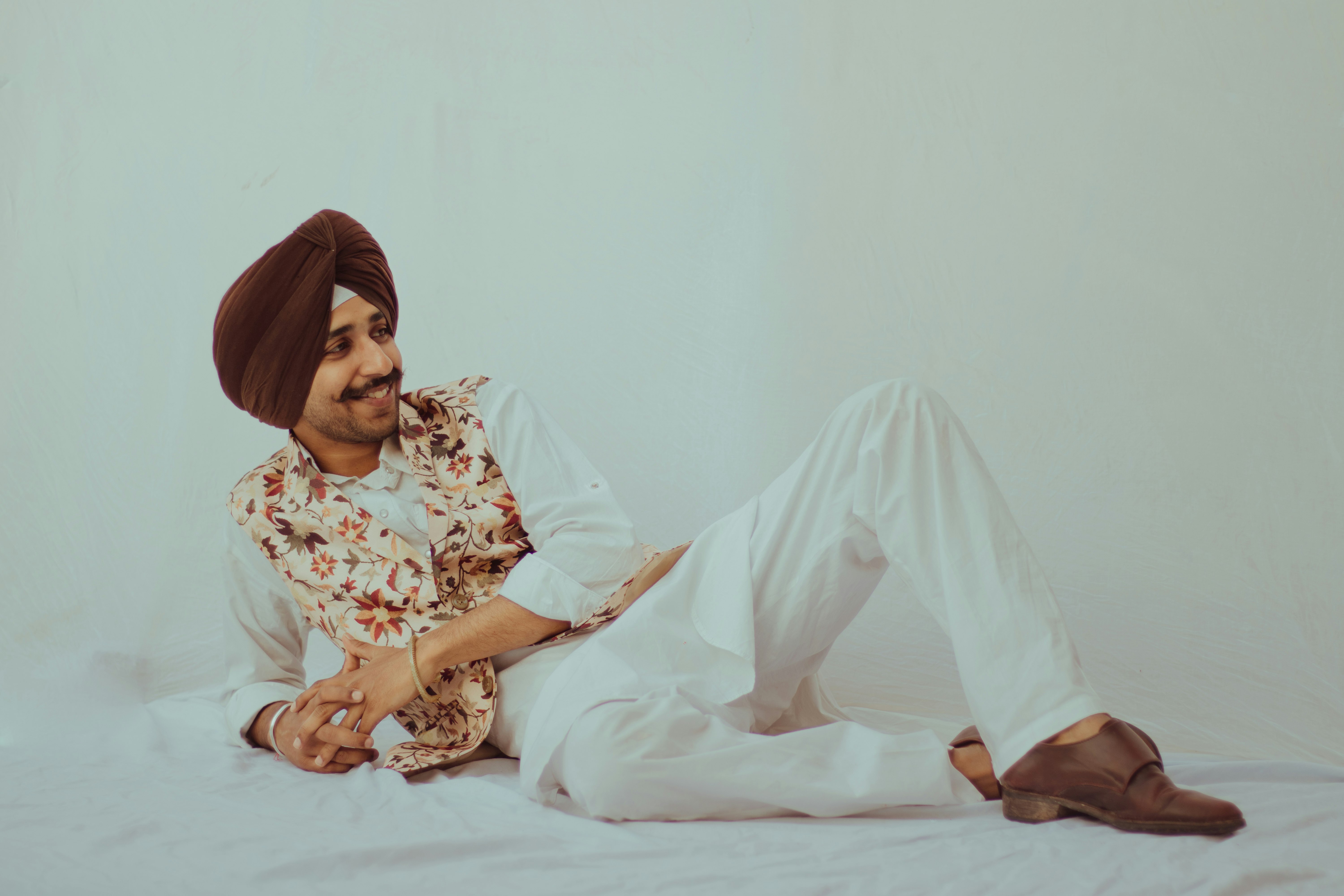 woman in white and brown floral dress sitting on white bed